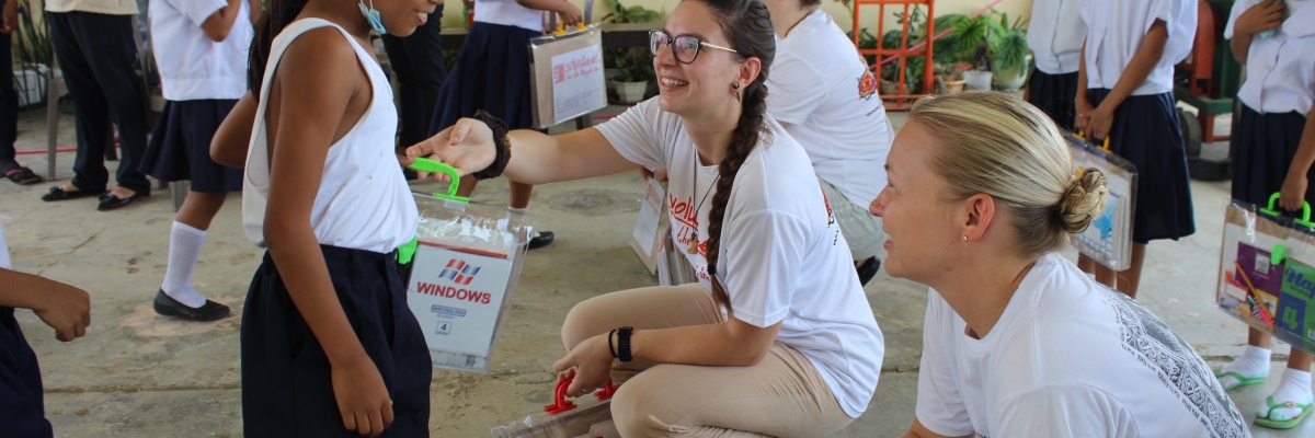 Distribution de fournitures scolaires lors d'une mission solidaire aux Philippines - Globalong Des bénévoles remettent du matériel scolaire à des élèves en uniforme dans une école primaire aux Philippines