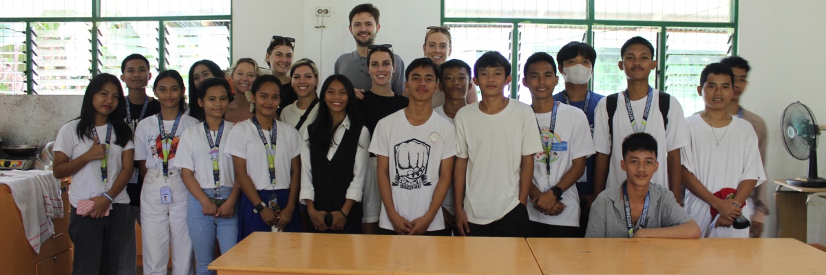 Rencontre entre bénévoles internationaux et élèves d’un établissement scolaire aux Philippines - Globalong Volontaires et étudiants posant ensemble dans une salle de classe pendant une mission éducative aux Philippines