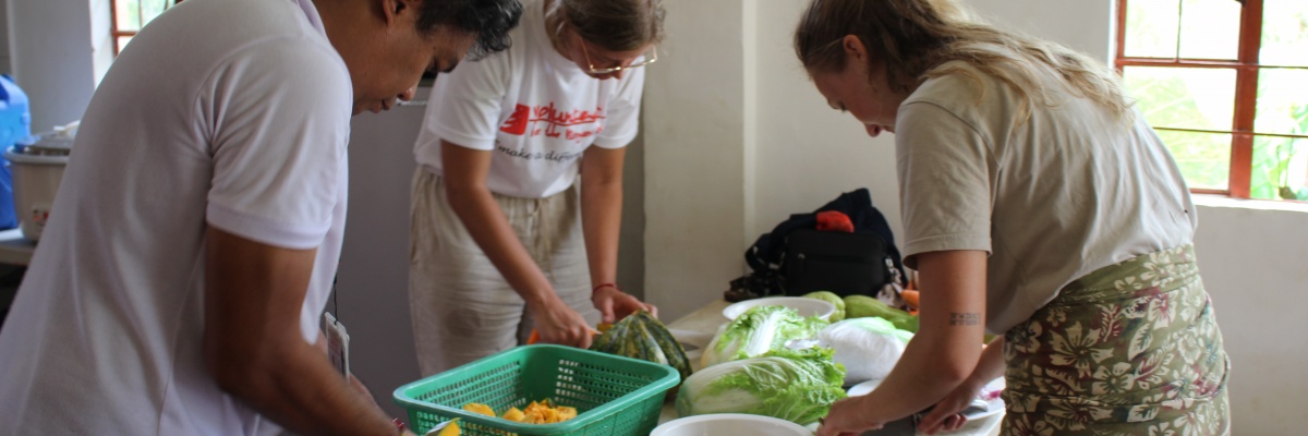 Immersion culturelle : atelier de cuisine traditionnelle pendant une mission de volontariat Des bénévoles internationaux participent à un atelier de cuisine locale en préparant des légumes frais aux Philippines - Globalong