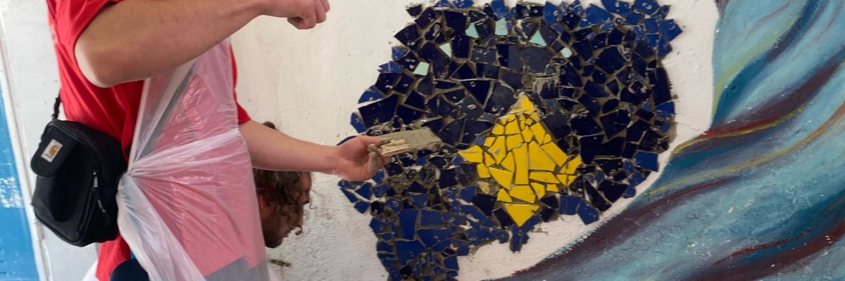 jeune bénévole réalisant une fresque sur la diversité dans un centre culturel solidaire