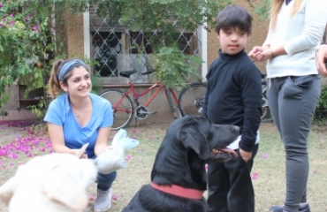 Un enfant entouré d'un chien noir et d'une volontaire souriante lors d'une séance de thérapie canine organisée par Globalong.