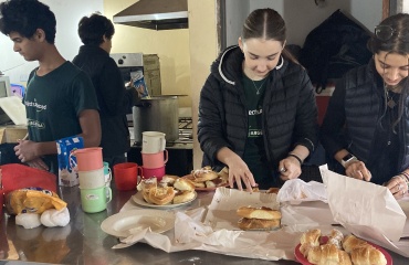 Des volontaires de Globalong préparent des repas dans une cuisine communautaire, découpant des viennoiseries et organisant des assiettes pour la distribution.
