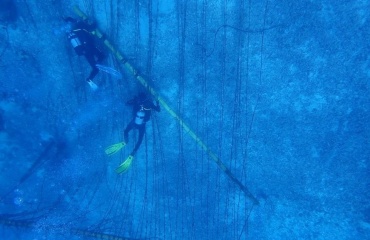 Deux plongeurs travaillant sous l'eau pour entretenir une pépinière corallienne, fixée à des structures sous-marines.