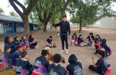 Un bénévole de Globalong animant un atelier éducatif en plein air avec des enfants assis en cercle à Cordoba, Argentine, sous de grands arbres.