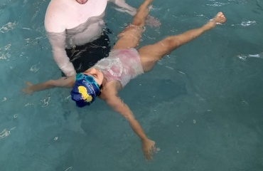 Bénévole de Globalong aidant une jeune fille à flotter dans une piscine lors d'une session d'apprentissage de la natation à Cordoba, Argentine.