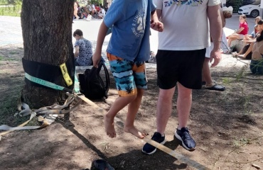 Un bénévole de Globalong aidant un jeune garçon à marcher sur une slackline tendue sous un arbre lors d'une activité en plein air à Cordoba, Argentine.