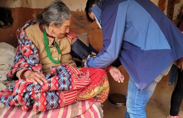 Volontaire Globalong en mission d’ostéopathie au Népal apportant des soins à une patiente âgée Mission de bénévolat en ostéopathie au Népal – un volontaire Globalong prodigue des soins à une femme âgée dans une maison rurale