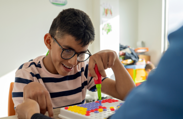 enfant en situation de polyhandicap participant à un atelier éducatif avec un bénévole en Espagne