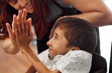bénévole encourageant un enfant en situation de polyhandicap avec un geste de high five