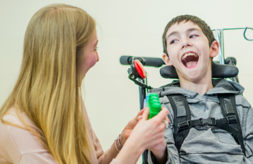 bénévole jouant avec un enfant polyhandicapé souriant dans un cadre d’accompagnement solidaire
