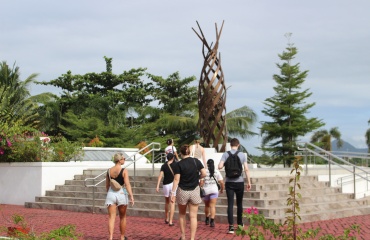 Groupe de volontaires marchant vers un monument moderne entouré de végétation tropicale aux Philippines