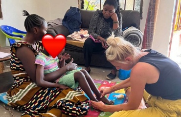 Bénévole souriant auprès d'un enfant utilisant un siège de soutien