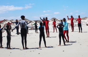 Groupe de jeunes échangeant avec une bénévole en bord de mer au Cap