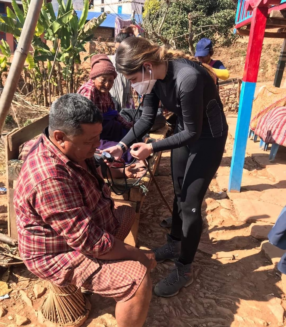 Bénévole en mission de santé et d’ostéopathie au Népal réalisant une consultation dans un village Mission de bénévolat en ostéopathie au Népal – une bénévole mesure la tension artérielle d’un patient lors d’une consultation dans un village rural
