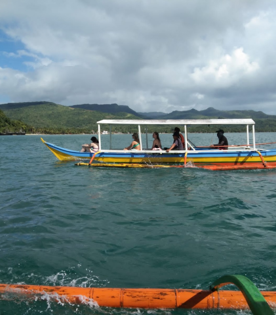 Volontaires en excursion sur un bateau traditionnel en bois sur une mer calme entourée de montagnes aux Philippines - Globalong 